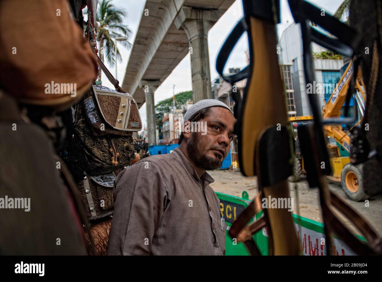 Il proprietario di un negozio di prodotti in pelle su STRADA CMH, Indiranagr. La recinzione di costruzione della metropolitana di Bangalore copre tutto tranne un ingresso stretto a questo negozio e alcuni altri negozi accanto ad esso. Ciò ha causato un netto calo dei clienti. Bangalore, Karnataka, India. 6 Maggio 2010. Uno dei set di immagini della storia fotografica, Bangalore Metro Rail – No Small Business, di Ayush Ranka. Foto Stock