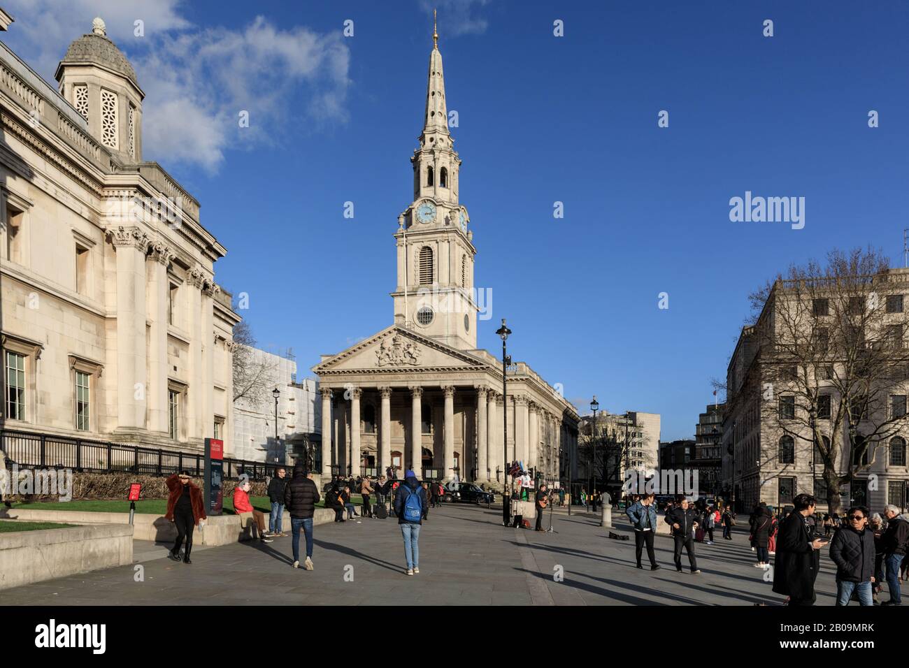 Persone su Trafalgar Square con St Martin nella chiesa Fields e la National Gallery al sole con cielo blu, Londra, Regno Unito Foto Stock