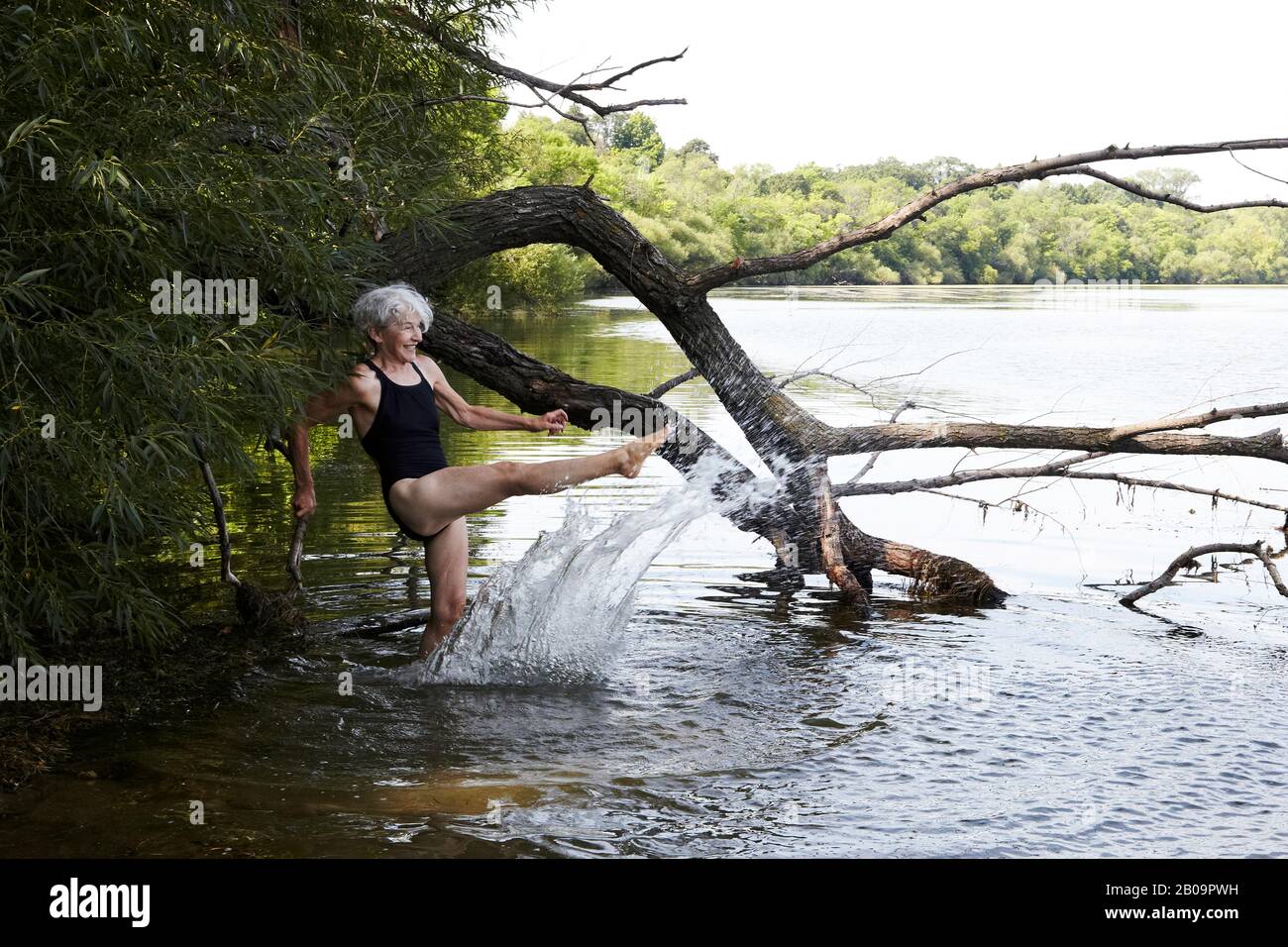 Donna anziana che indossa un costume da bagno che si tuffa nel lago Harriet. Foto Stock