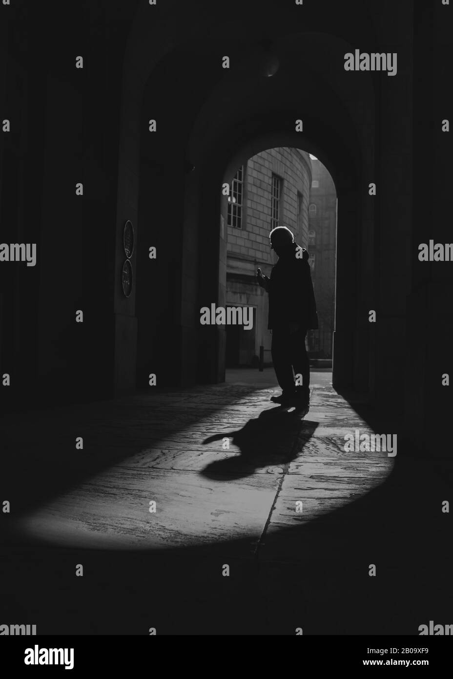 Una persona solitaria entra alla luce in una città affollata. Foto Stock