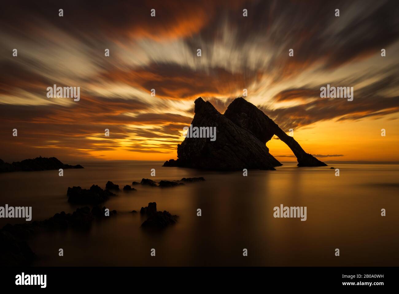 Arco di roccia del violino di riflessione di luce di sunrise, Portknockie, Scozia Foto Stock