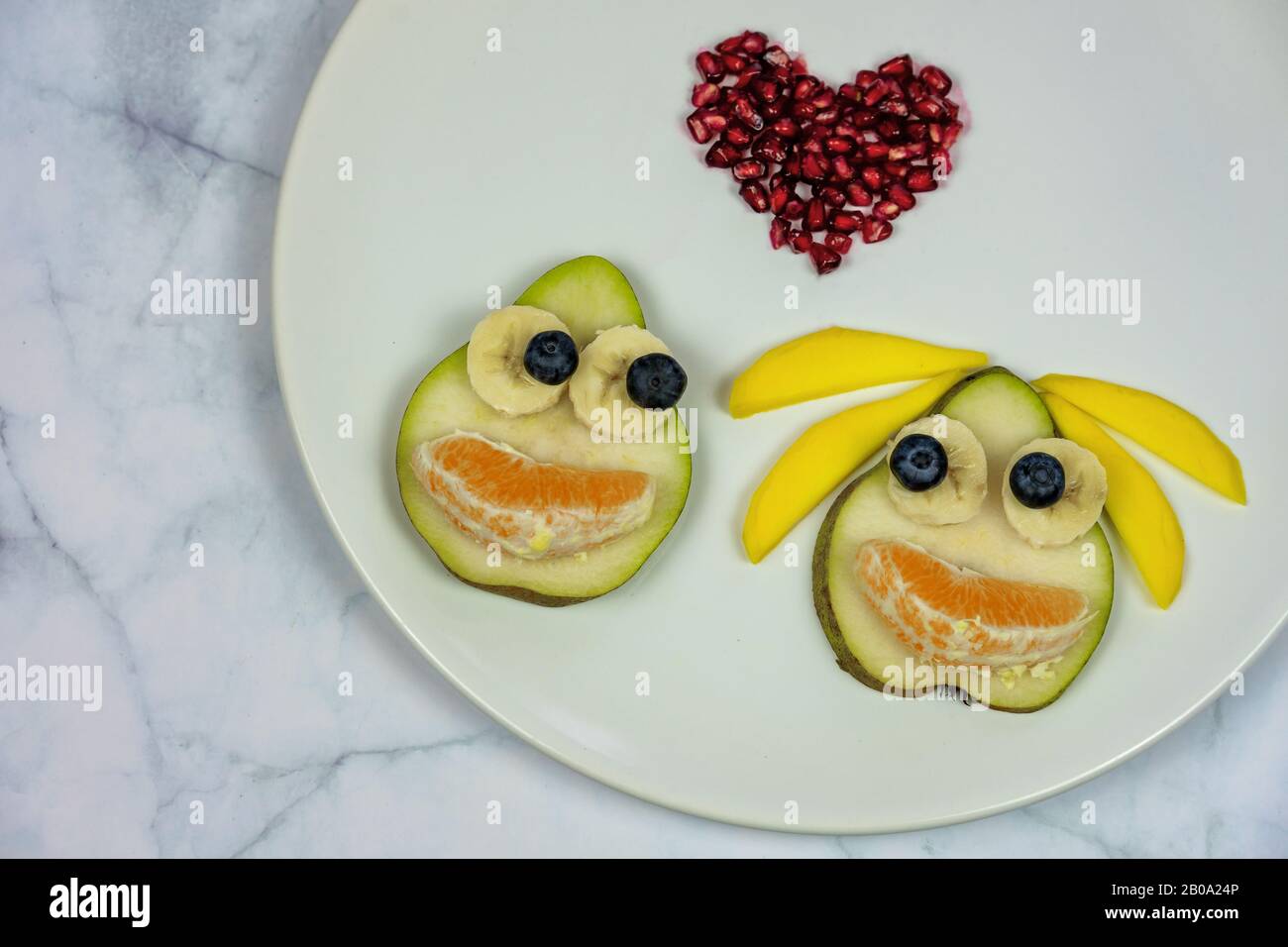 divertente coppia di pere si affaccia in amore con la forma del cuore su un piatto bianco. Foto Stock
