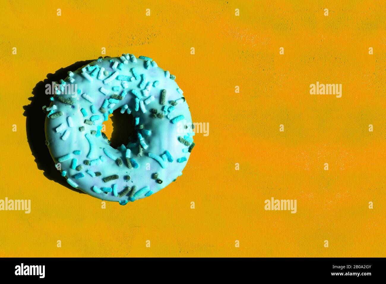 Ciambella di mentolo su sfondo arancione. Deliziosa ciambella colorata con glassa e ripieno. Disposizione piatta, spazio di copia Foto Stock