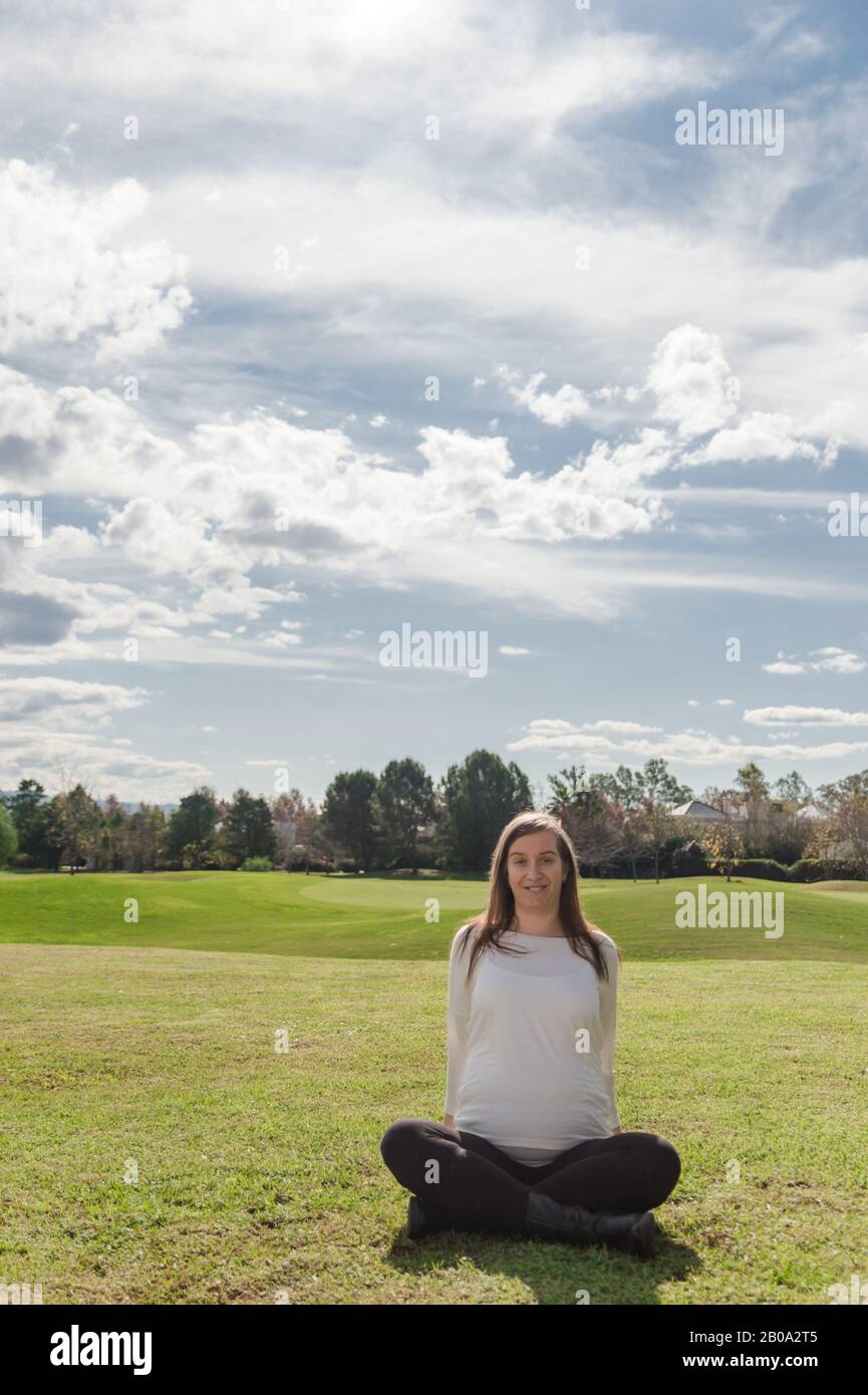 Donna incinta di 30 anni che posa in nido con paesaggio naturale sullo sfondo Foto Stock