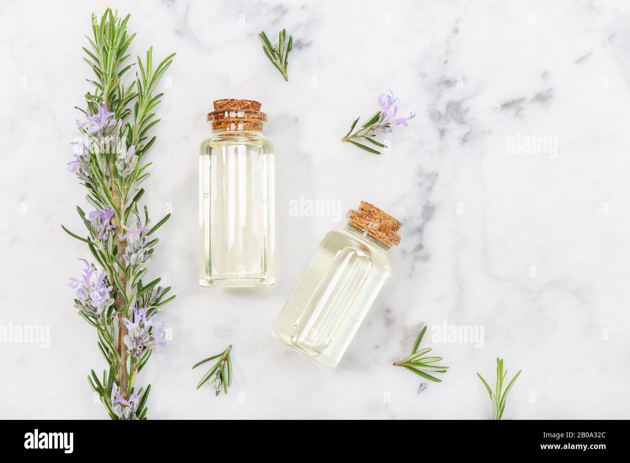 Olio essenziale di rosmarino in bottiglia di vetro e ramoscelli sul tavolo di marmo. Olio di Salvia Rosmarinus. Vista dall'alto Foto Stock