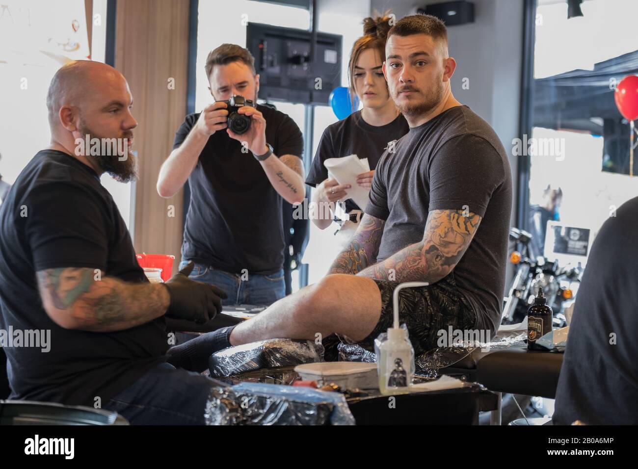 Uomo che ottiene un tatuaggio alla Harley-Davidson Lettura Berkshire Inghilterra con gli onlookers Foto Stock
