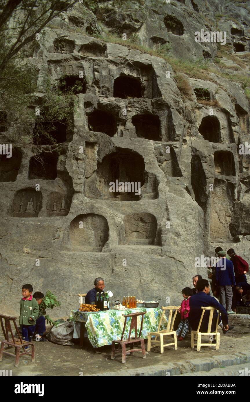 CINA, GROTTE DI LUOYANG LONGMEN, STATUE BUDDISTE SCAVATE NELLE SCOGLIERE ROCCIOSE, GENTE CHE VENDE SPUNTINI Foto Stock