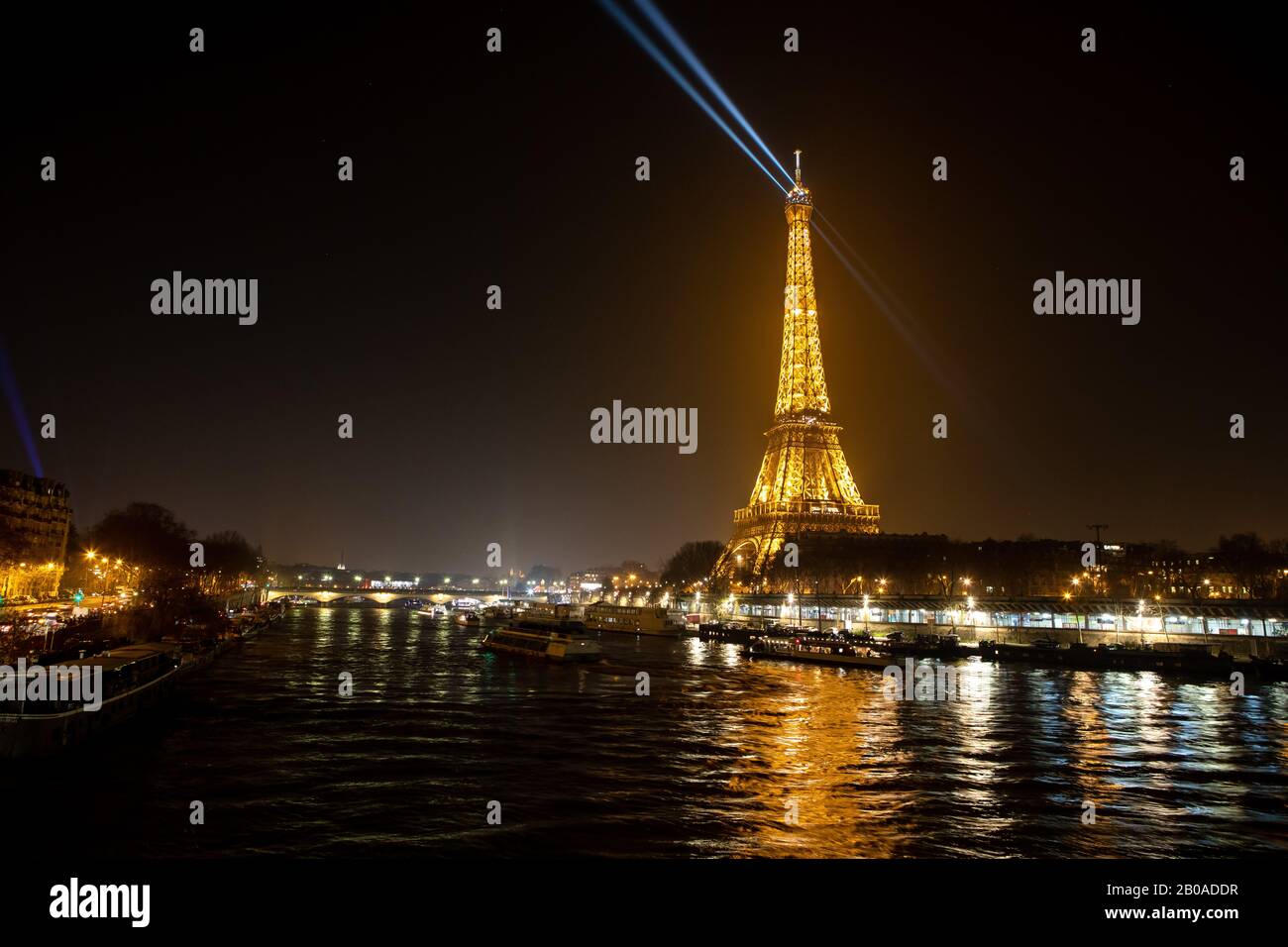 La Torre Eiffel e i suoi caratteristici riflettori visti sopra la Senna Foto Stock