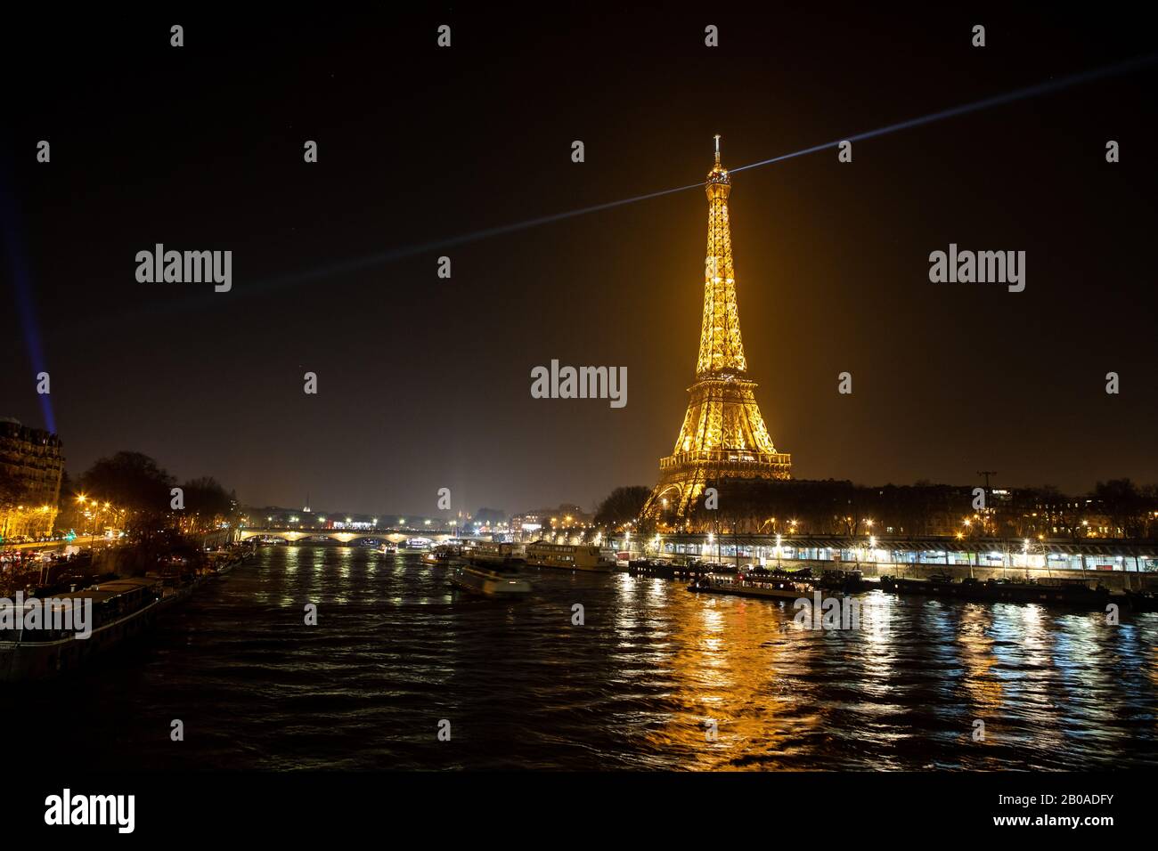 La Torre Eiffel e i suoi caratteristici riflettori visti sopra la Senna Foto Stock