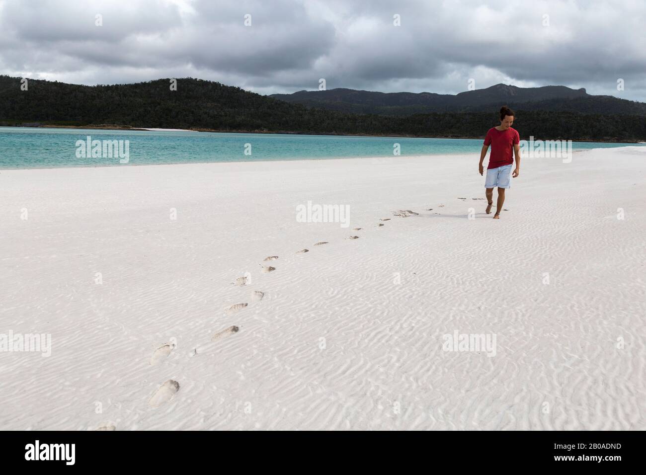 Turista con una camicia rossa a piedi sulla spiaggia di sabbia bianca australiana Foto Stock