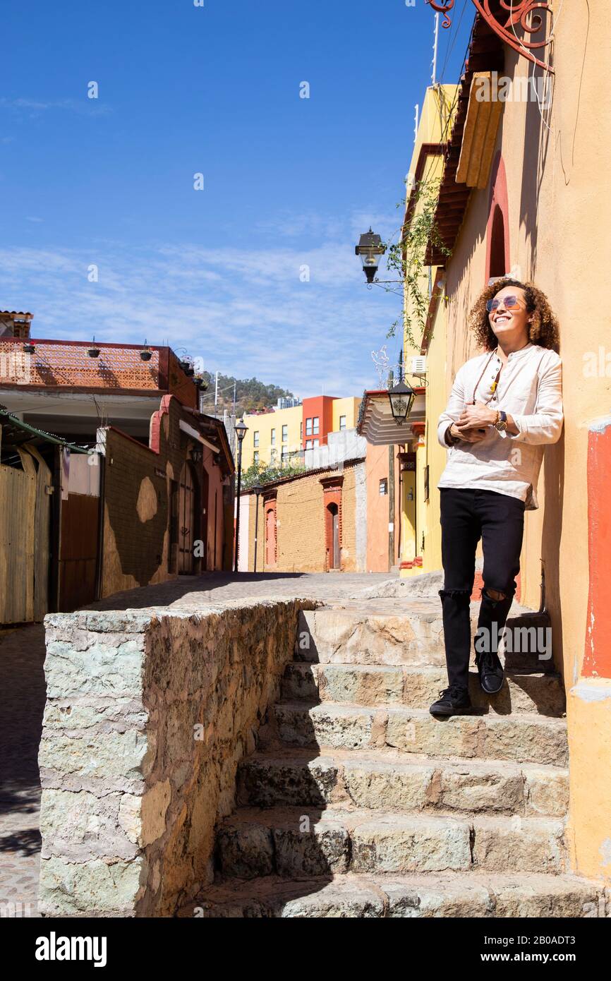 Uomo appoggiato sul muro giallo di edificio coloniale a Oaxaca, Messico Foto Stock