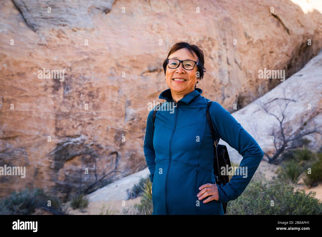 Ritratto di sorridente Senior Asian Woman escursioni nel paesaggio desertico Foto Stock