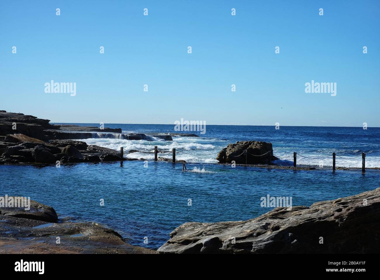 Nuoto giri backstroke nel rettangolo blu di Mahon Pool sul bordo dell'Australia sotto un cielo blu nuvoloso Foto Stock