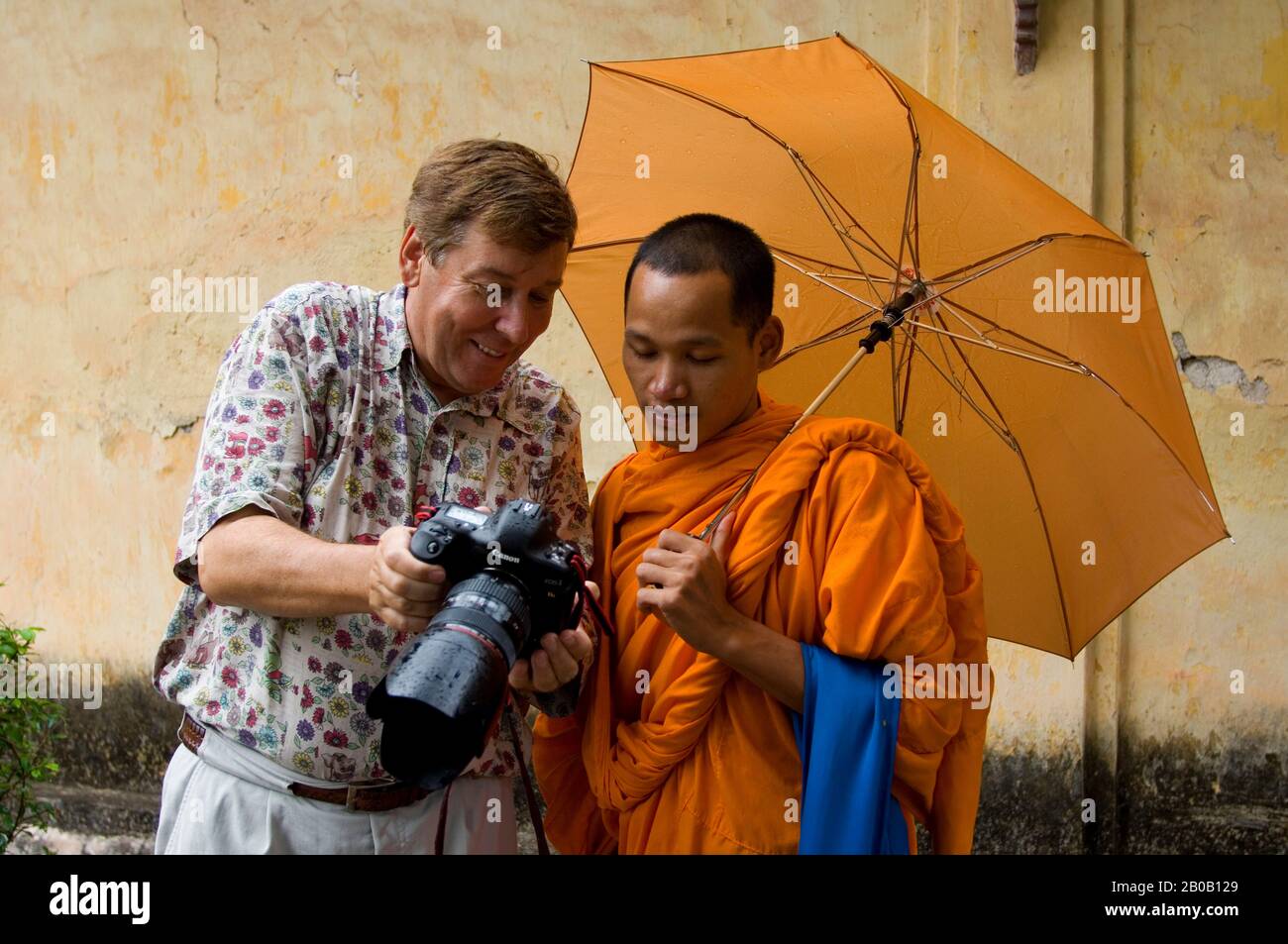 LAOS, VIENTIANE, VAT SISAKET, NOVIZIO CON OMBRELLO, TURISTA MOSTRANDOGLI IMMAGINE DIGITALE Foto Stock