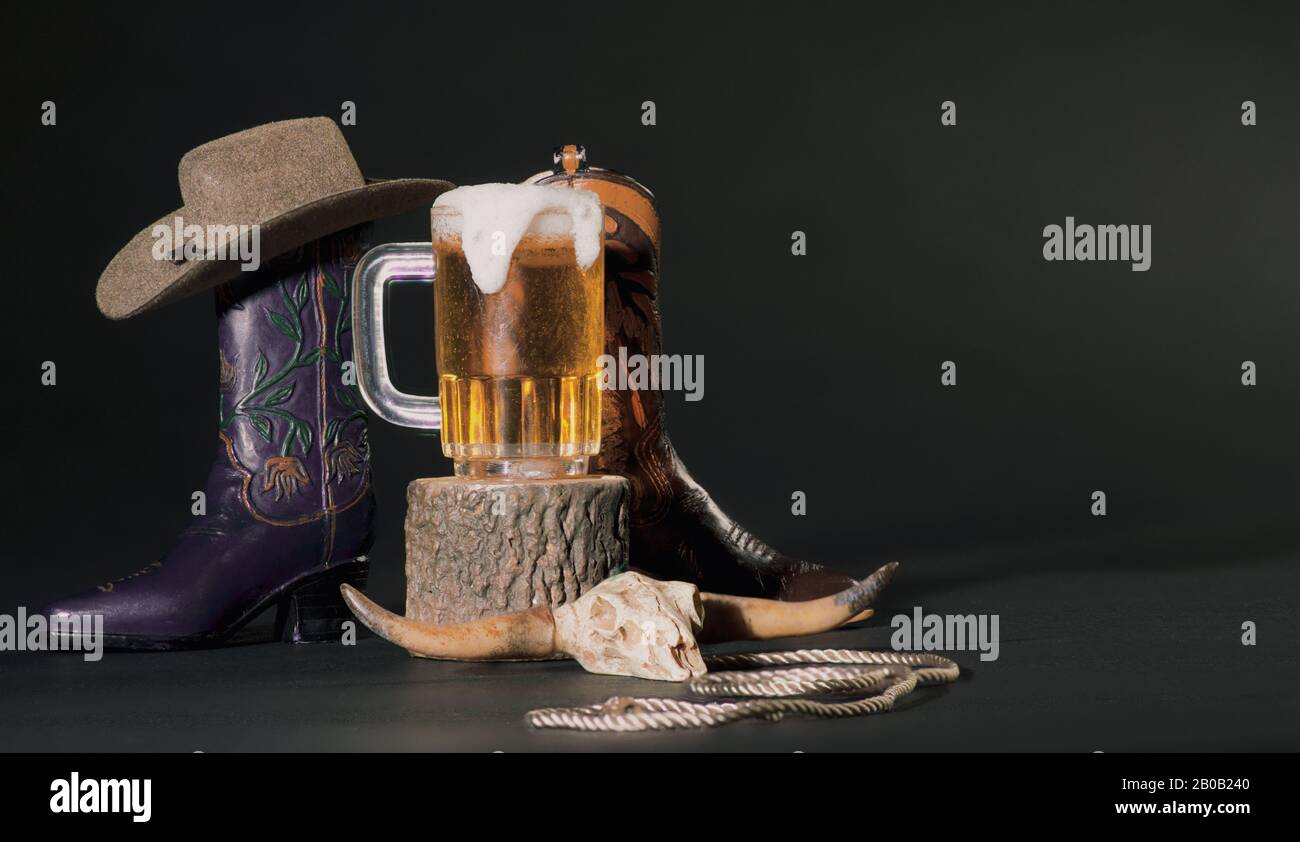 Texas Cowboy Tan Hat, Boots, Cow Skull, Pitcher Of Beer, Lasso Su Sfondo Scuro Foto Stock