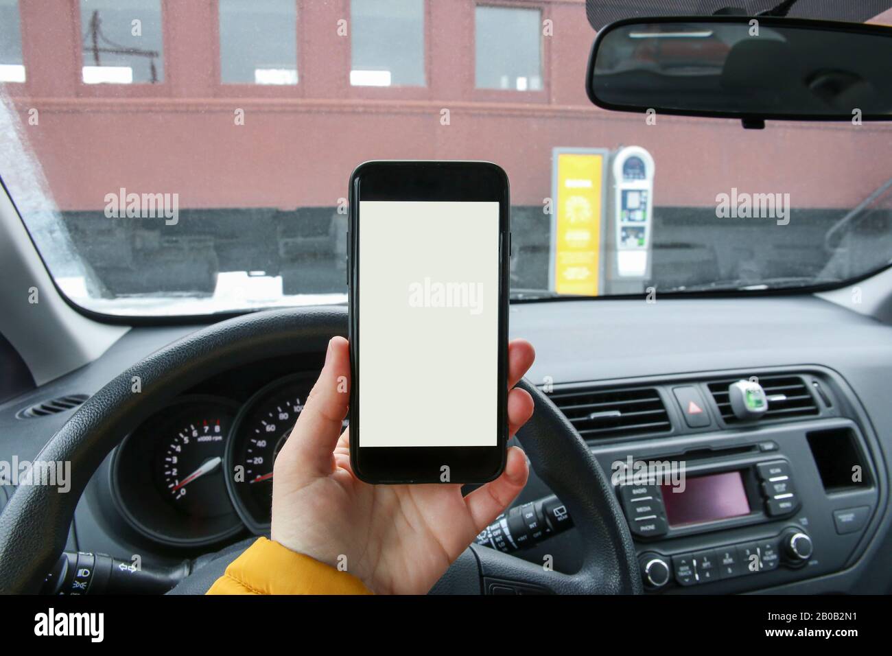 Donne Hands Holding un telefono con un'app di parcheggio sullo Schermo. Abitacolo Del Veicolo, Vista Del Conducente. Foto Stock