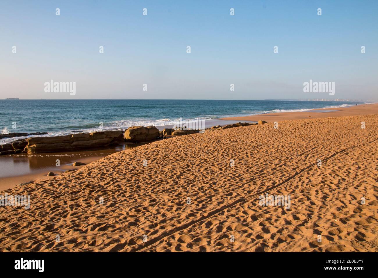 Vasta striscia di sabbia da spiaggia con rocce in shamows Foto Stock