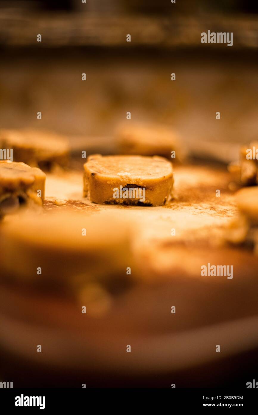 Pasta di biscotti con pezzetti di cioccolato non cotta su una pietra da forno con sfondo sfocato Foto Stock