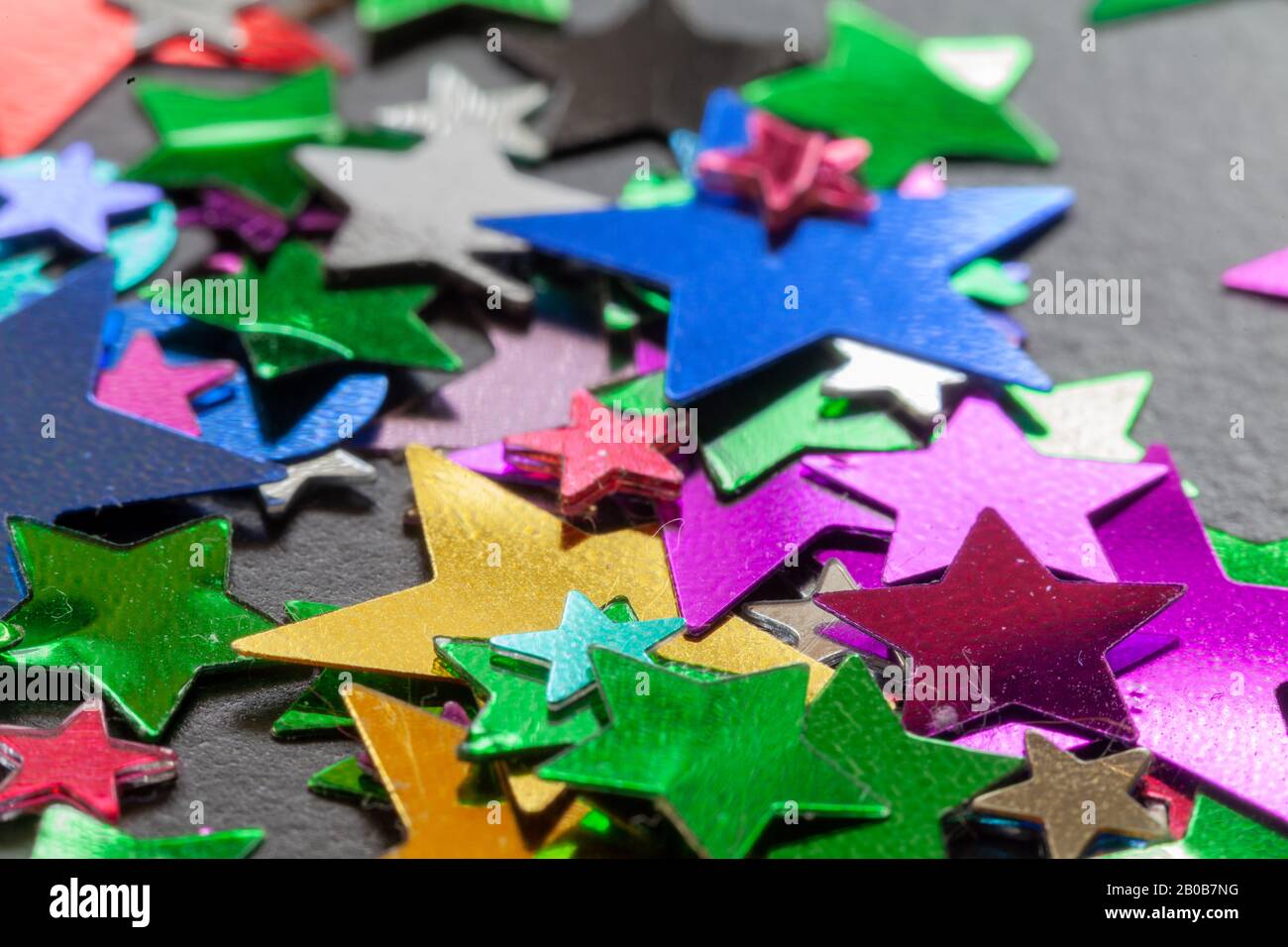 Party confetti multicolori stelle e forma primo piano scandito su un tavolo nero Foto Stock