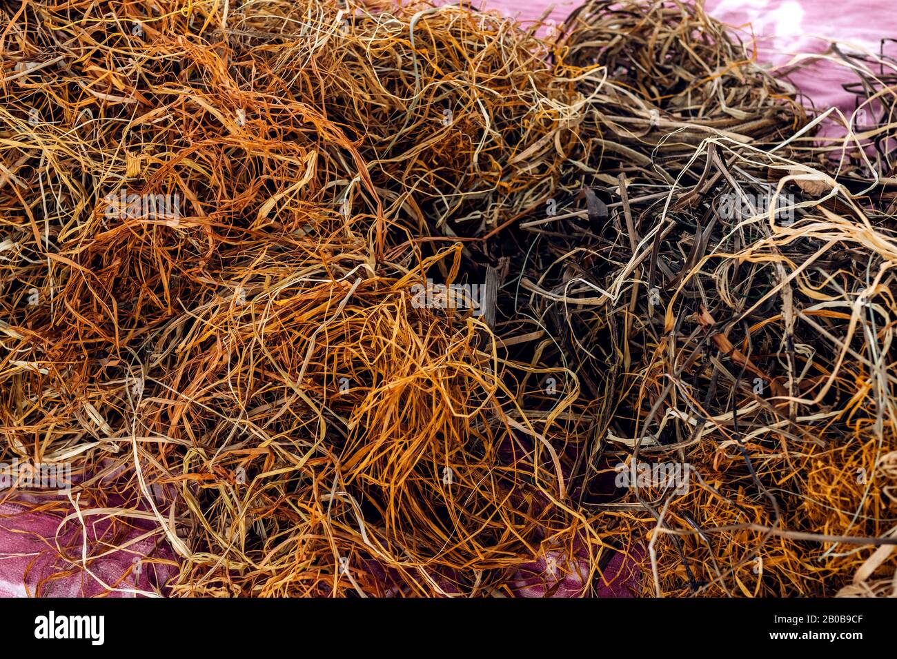 I thread aggrovigliati astraggono lo sfondo del motivo texture. Grande mucchio di corde di filo di tessitura naturale sparse casualmente come gli spaghetti sul tappeto. Laboratorio di tessitura artigianale. Foto Stock