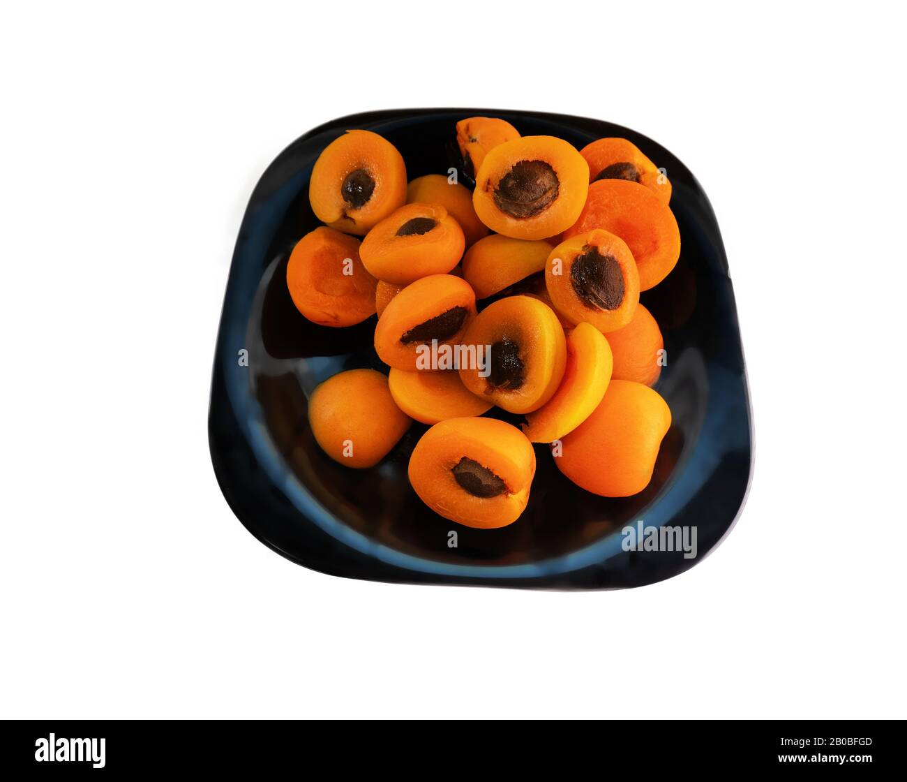 Metà delle albicocche con pietra su un piatto nero. Il contrasto dei colori. Isolare su sfondo bianco Foto Stock