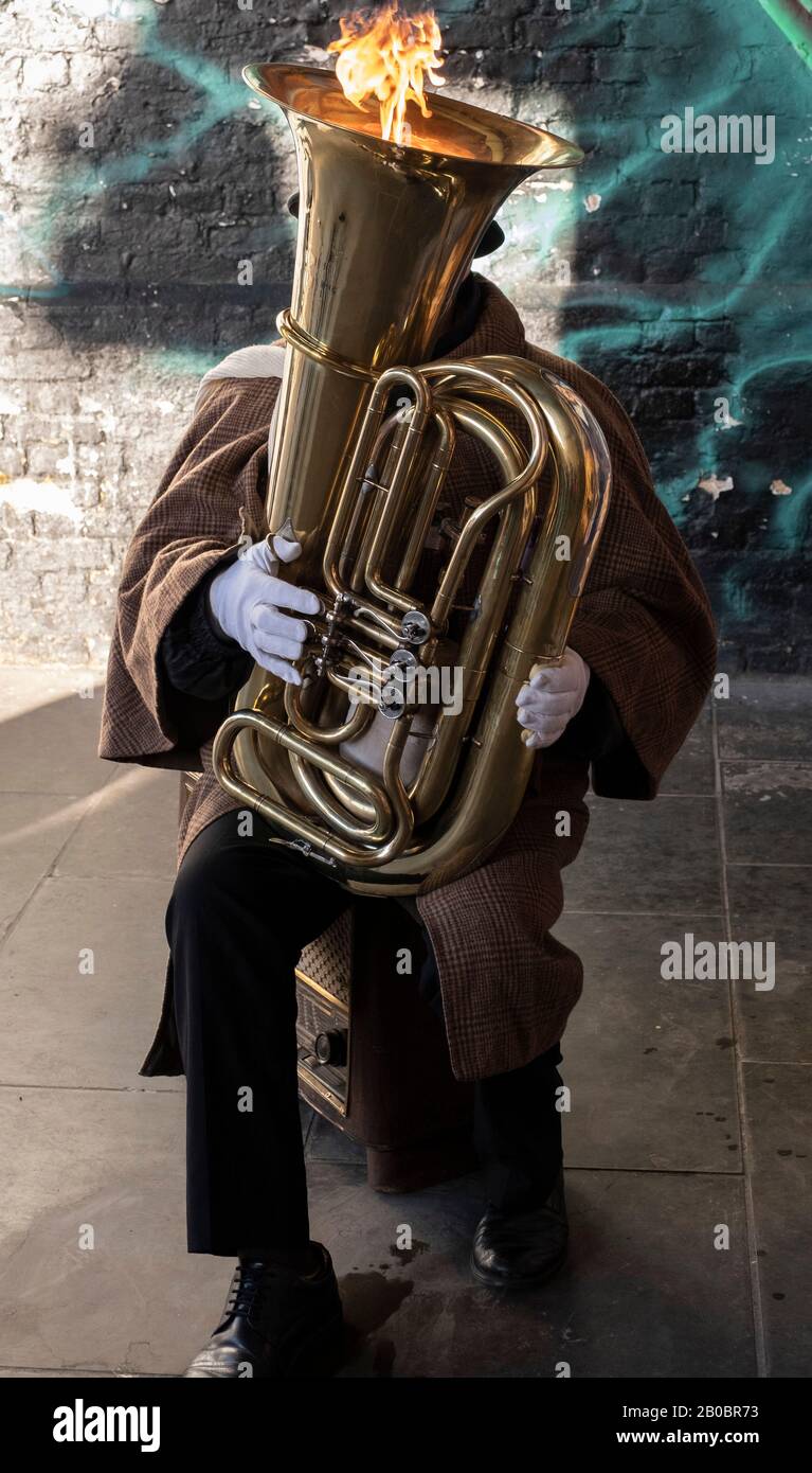 Busker suonando tuba con il fuoco soffiato da esso a Londra Foto Stock