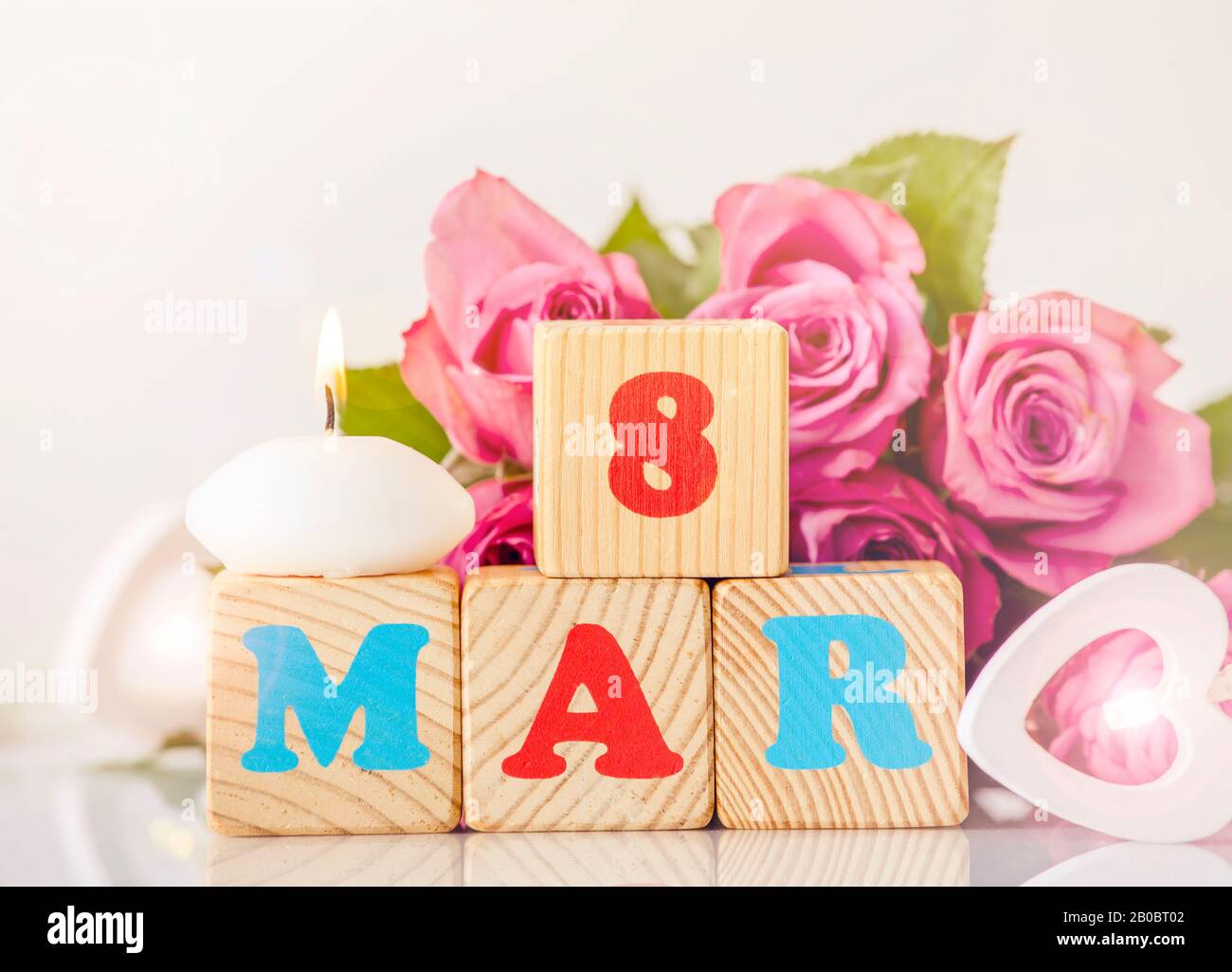 Calendario Internazionale della Giornata della Donna sfondo biglietto d'auguri. Con cuore di legno, rilassante candela a fuoco e bouquet decorativo rosa rosa sullo sfondo. Foto Stock