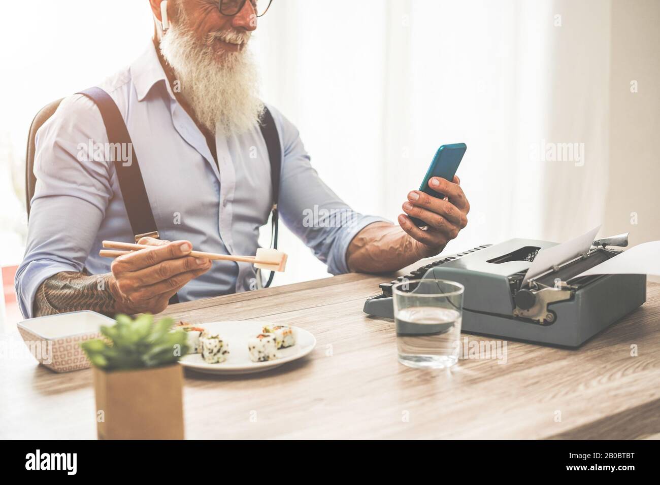 Architetto alla moda tatuato mangiare sushi a pranzo mentre si lavora al nuovo progetto - imprenditore Senior all'interno dello studio creativo - tendenze Moderne e anche Foto Stock