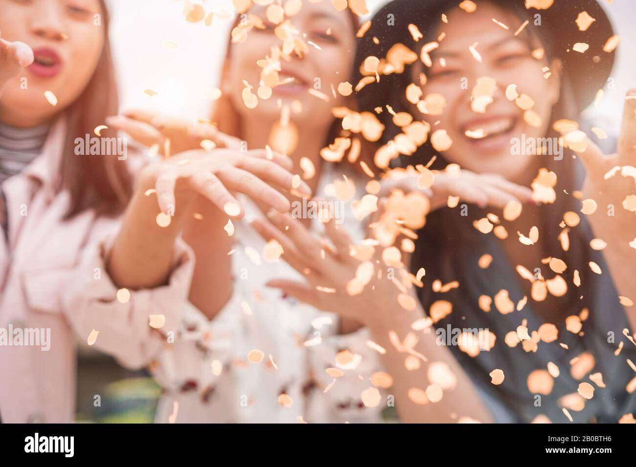 Gli amici asiatici sfocati che si divertono a lanciare confetti al party all'aperto - giovani alla moda che si divertono all'evento del festival - Hangout, amicizia, tendenze e gioventù Foto Stock