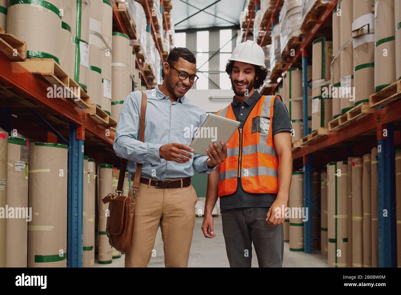 Bank manager che mostra le opzioni di prestito al responsabile del magazzino utilizzando un tablet digitale in fabbrica moderna Foto Stock