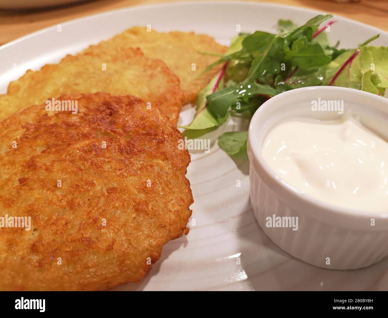 Frittelle di patate servita su piastra bianca con panna acida Foto Stock