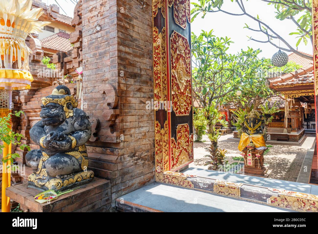 Porte d'ingresso al tempio indù con porte intagliate in legno e statua del guardiano dvarapala. Canggu, Badung, Bali. Architettura tradizionale e classica Balinese. B Foto Stock