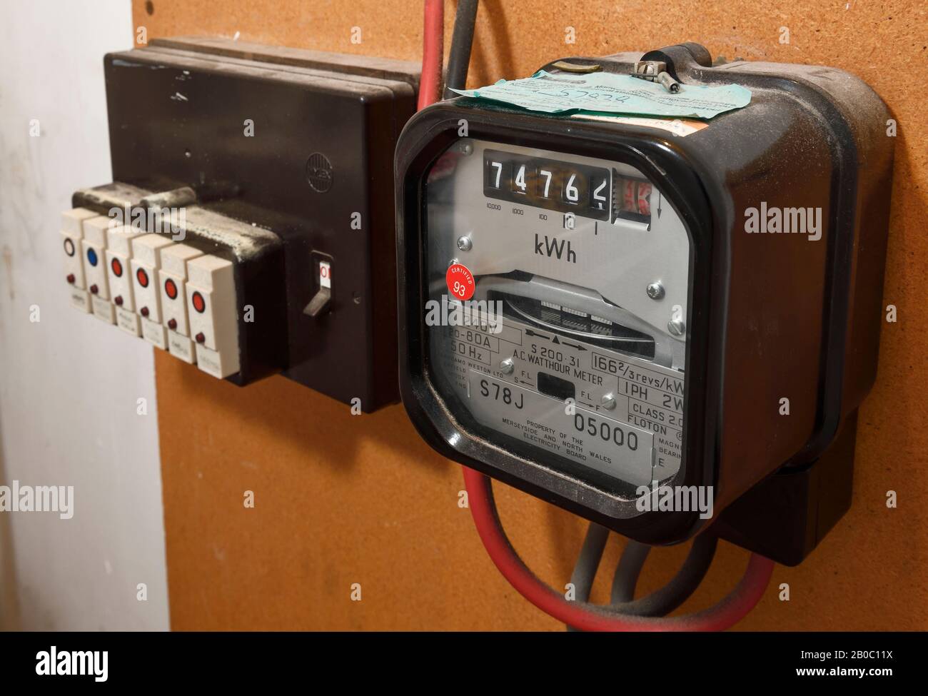 Un contatore elettrico meccanico di vecchio stile accanto a una fila di fusibili a innesto Foto Stock