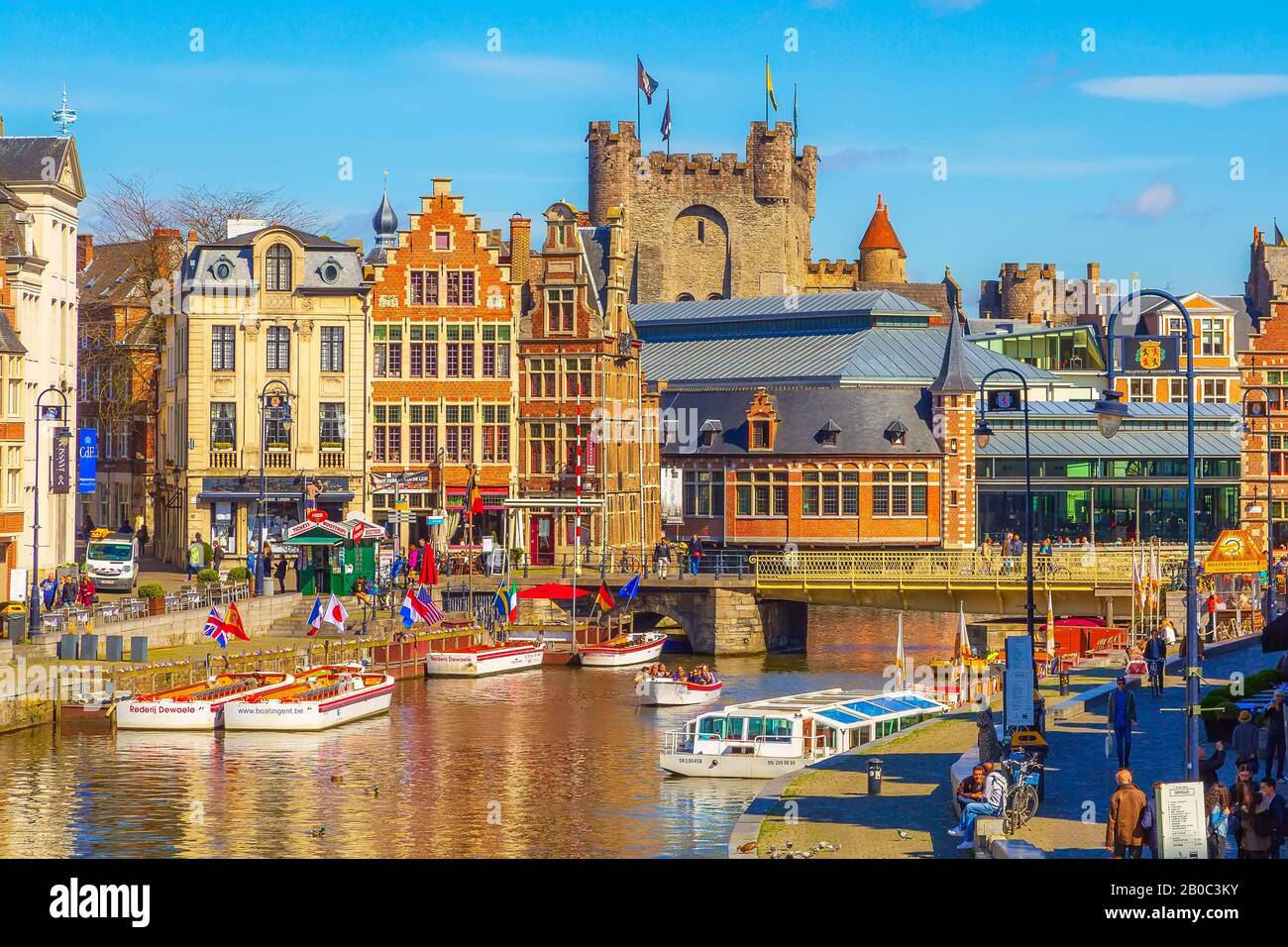 Gand, Belgio - 12 aprile 2016: Vecchie case tradizionali colorate lungo il canale, barche, castello di Gravensteen a Gand Foto Stock