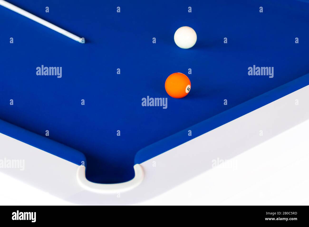 Un tavolo da biliardo blu con un cue, arancione numero cinque palla e la palla bianca Foto Stock