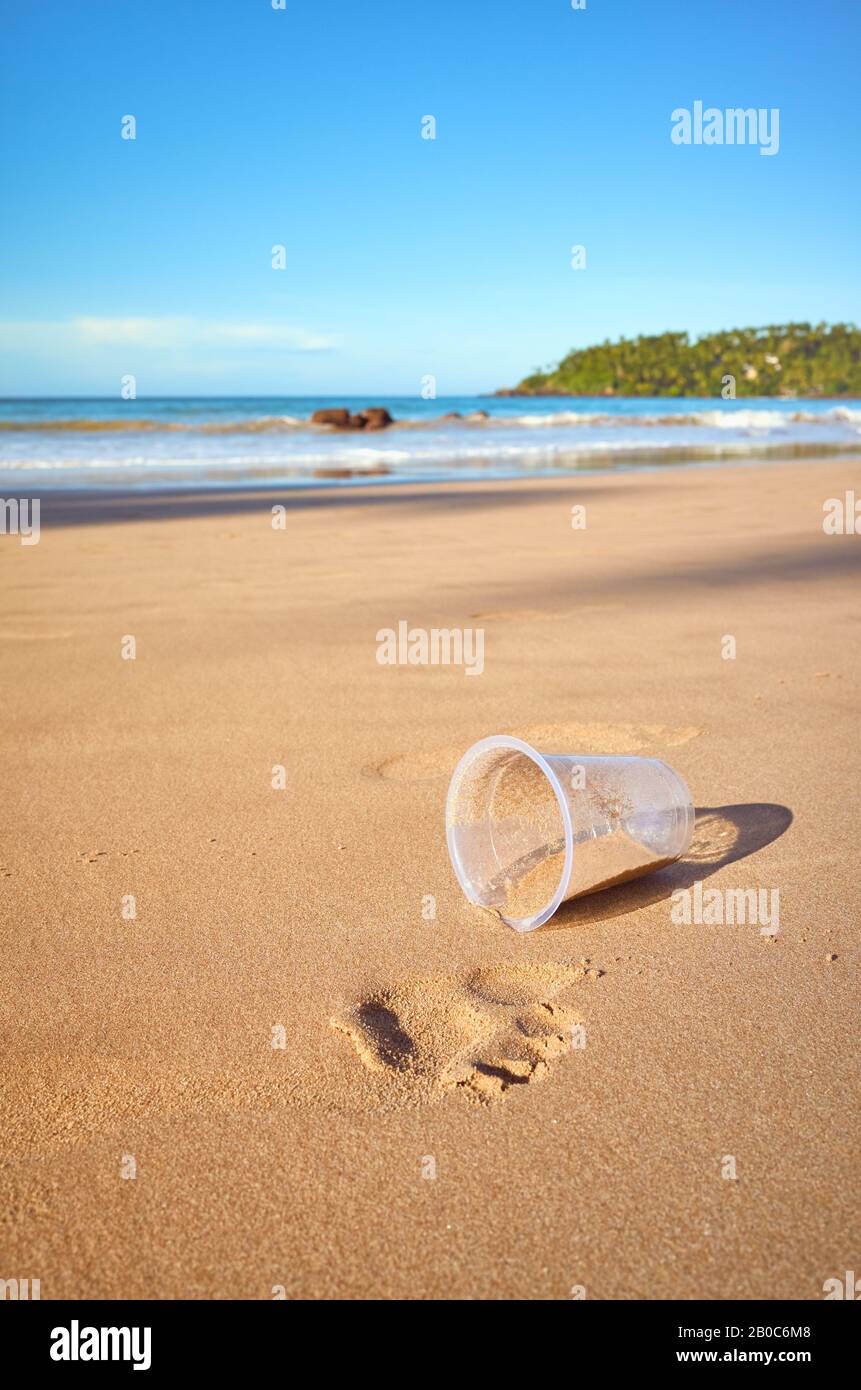 Tazza di plastica su una spiaggia tropicale, fuoco selettivo. Foto Stock