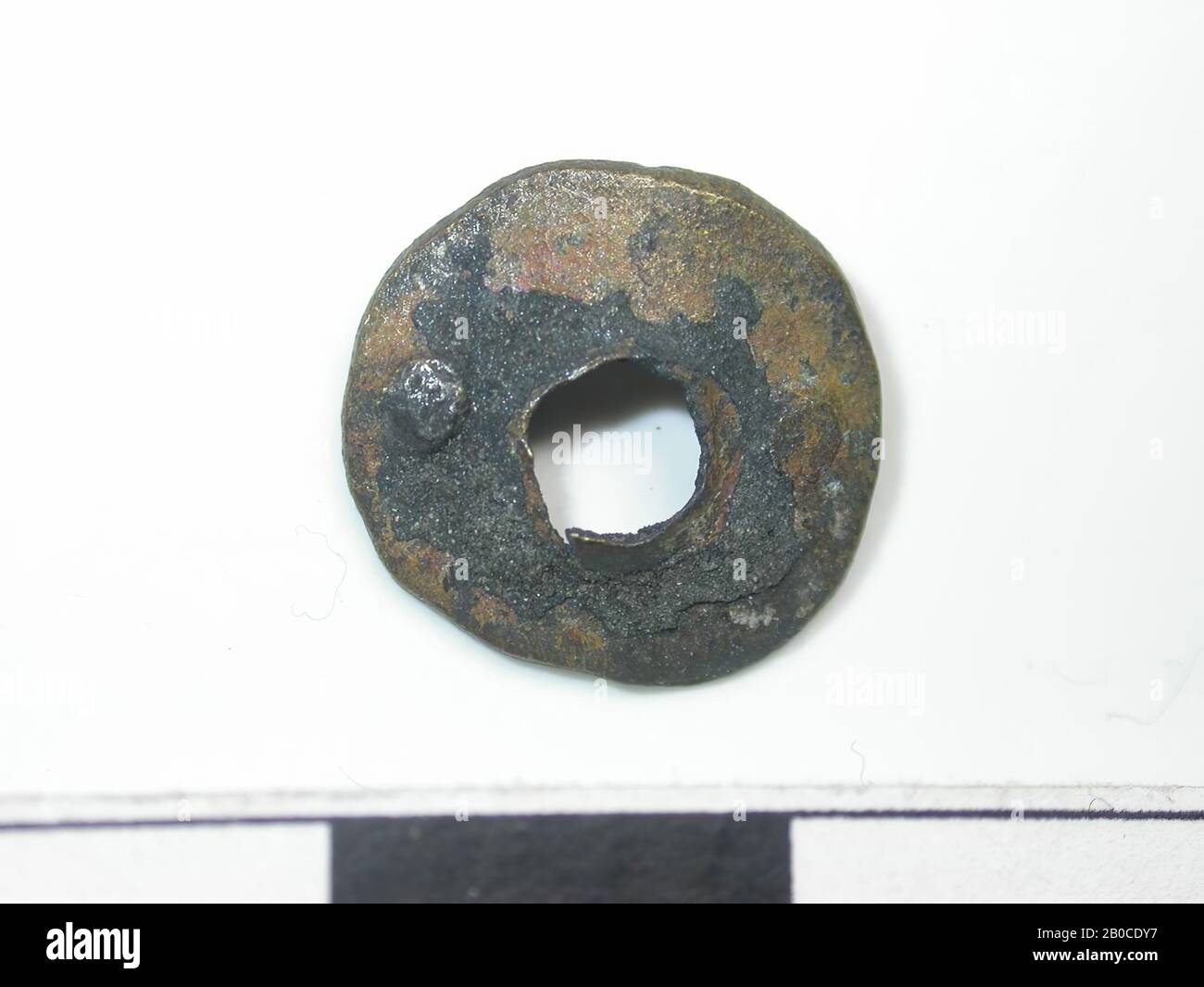 Cerchio con foro al centro, color oro (lega di rame). Tocco nero sulla superficie. Danneggiato ai bordi del foro. La parte posteriore è piatta. montaggio a 2 pin. I perni sono rotondi e passano attraverso il cerchio. La lunghezza dei perni è di 0,2 cm. Il diametro dei perni è di 0,2 cm. Il diametro del foro è 0,4 cm, corsa del nastro, metallo, lega di rame, Dm: 1,3 cm, D: 0,1 cm, fine del 14th secolo 1350-1400, Olanda, Zeeland, Hulst, Verdronken Land Foto Stock