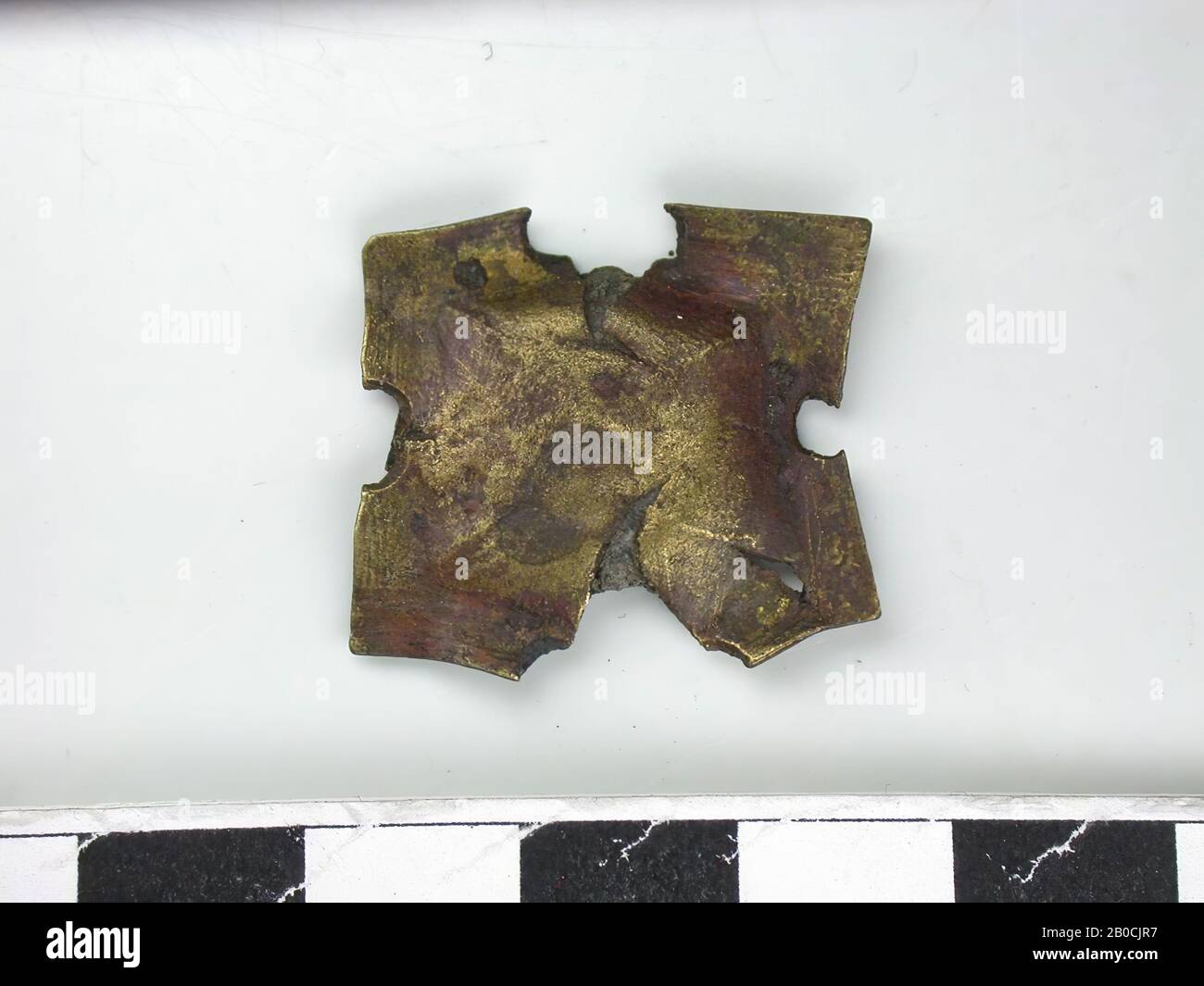Forma quadrata, oro (lega di rame). Quadrato con mezzo cerchio tagliato al centro di ogni lato. Successivamente, è stata eseguita una forma quadrata verticale. La pastella è strappata all'ingresso a forma di semicerchio., la parte posteriore presenta una striscia di fissaggio (L: 2,1 cm), simile ad una copiglia, con resti di pelle tra loro, corsa della cintura, metallo, lega di rame, L: 2, 5 cm, W: 2,3 cm, H: 0,3 cm, fine del 14th secolo 1350-1400, Paesi Bassi, Zelanda, Hulst, Verdronken Land Foto Stock