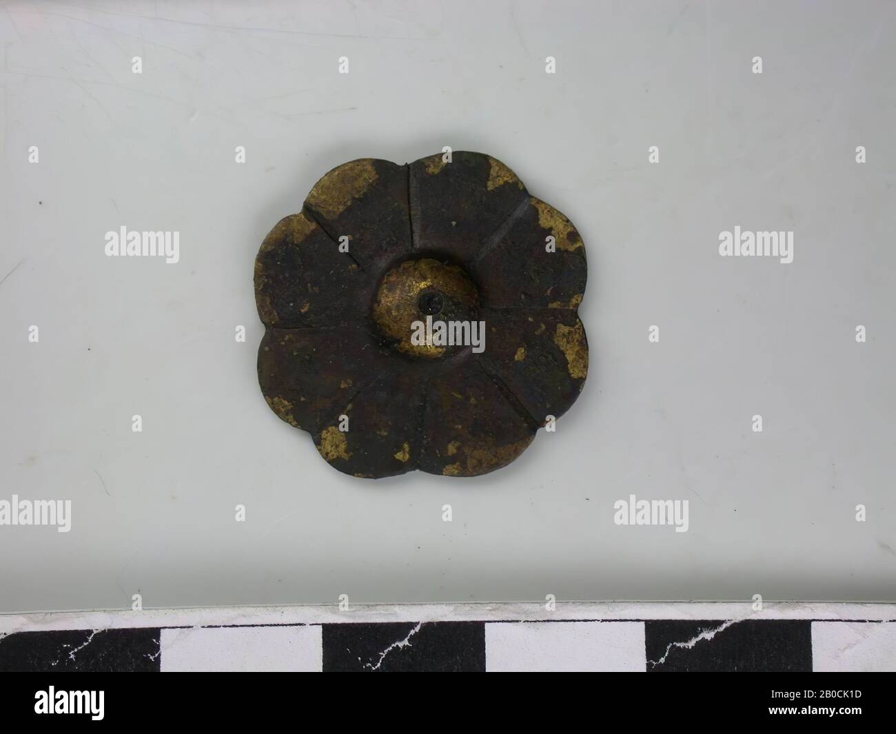 8-letto figura, oro-colorato (lega di rame). Figura a otto lobi con un emisfero al centro con un foro in esso. Intorno ad esso ci sono otto lobi separati l'uno dall'altro da una tacca. La parte posteriore è un negativo della parte anteriore. La schiena è fortemente resistente agli agenti atmosferici., Corsa Del Nastro, metallo, lega di rame, diam: 2,3 cm, H: 0,4 cm, fine 14th secolo 1350-1400, Paesi Bassi, Zeeland, Hulst, Verdronken Land Foto Stock