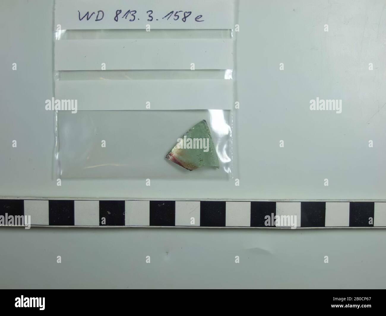 Frammento di vetro da setaccio campioni traccia 22, 1 frammento di parete di vetro verde chiaro con poche piccole vescicole, striscia rossa traslucida, spessore 2,0 mm parete, frammento, vetro, Paesi Bassi, Utrecht, Wijk bij Duurstede, Wijk bij Duurstede Foto Stock