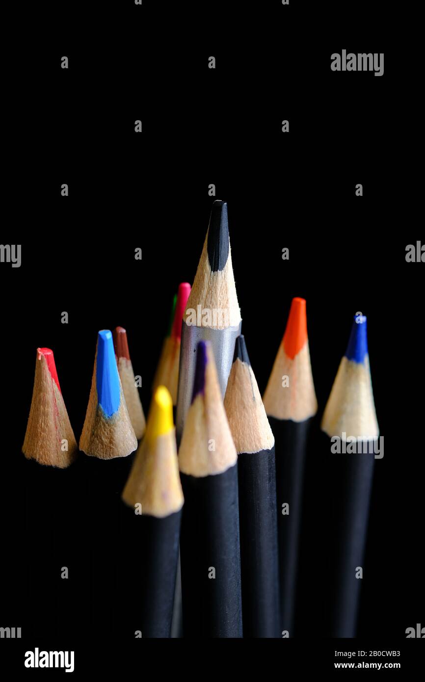 Set di matite colorate con una matita nera che si alza sopra e si alza dagli altri Foto Stock