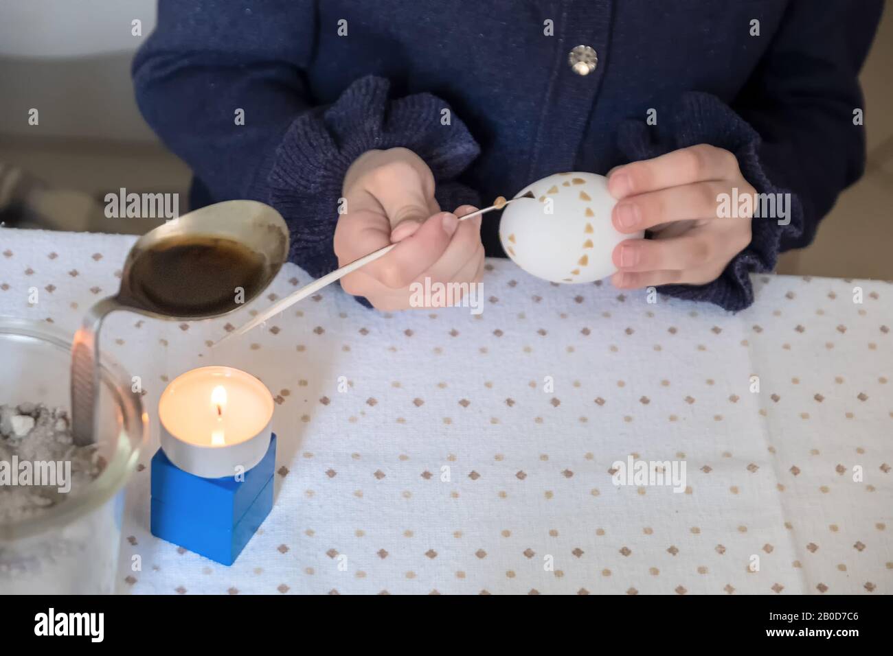 La mano del bambino dipinge un uovo di Pasqua dopo la tradizione sorbian con la piuma d'oca tagliata e cera della candela. Foto Stock