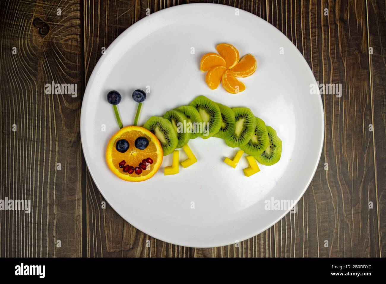 divertente verme di frutta su piatto bianco dolce sano per i bambini su tavola di legno . Foto Stock