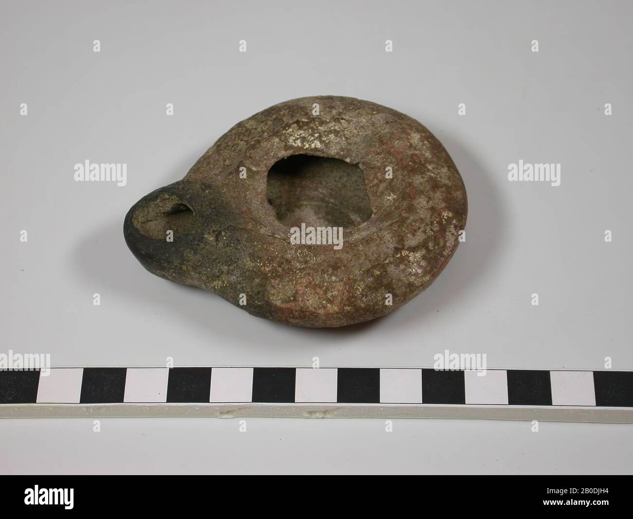 La lampada ha una base piatta ma non chiaramente contrassegnata. Le pareti hanno una forma leggermente convessa. Il bordo scorre quasi orizzontalmente verso l'interno e l'estremità è inclinata verso il basso. Il beccuccio è una sporgenza della forma circolare di base della lampada. Il colore è rosso con una decolorazione nera intorno al beccuccio a causa di bruciature, stoviglie, terracotta, D max 6,9 cm, H 2,1 cm, D edge 4,1 cm, D lancio 1,4 cm, periodo romano 63 a.C. - 324 d.C., Palestina Foto Stock