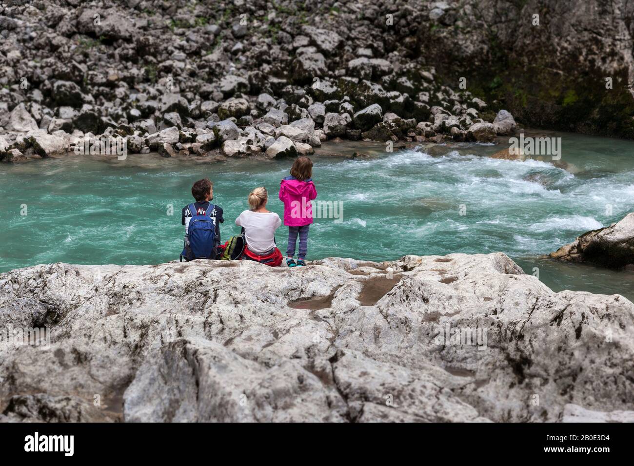 famiglia riposante dopo il trekking sulle rocce sulla riva di un fiume selvaggio di montagna Foto Stock