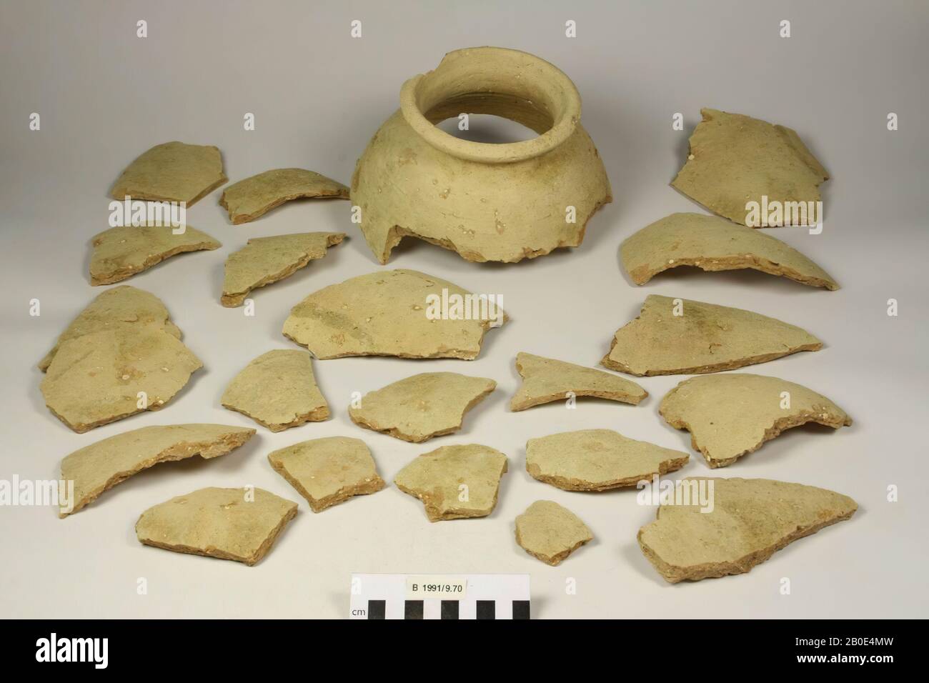 Frammenti sciolti appartenenti ad una grande pentola di argilla cotta. Le spalle sono convesse e inclinate verso l'interno. Il collo è stretto e concavo. Il bordo è ispessito all'esterno e pizzicato. Fabbricato sulla ruota. L'argilla è di colore marrone chiaro, ha una consistenza media e dura ed è agglutinata con inclusioni rosse e grigie (possibilmente piccole parti di ceramica) e calce. All'esterno un rivestimento beige con tracce di attrito, piccoli pezzi di argilla in eccesso e depositi verdi. All'interno un rivestimento arancione con segni di torsione, piccole crepe e craquelures. Parte della superficie è leggermente rigata. Piccola Foto Stock