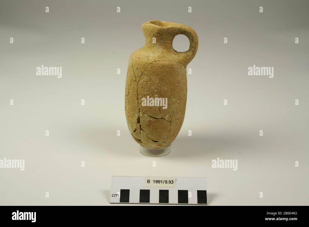 Una brocca in terracotta con un piccolo fondo rotondo e un corpo cilindrico. Sulla spalla la parete è inclinata verso l'interno da una curva affilata e si fonde in un collo concavo basso. Il bordo è verso l'esterno ed è immaturo. Un lato del bordo viene pizzicato su un tubo di lancio. Sull'altro lato è presente una maniglia verticale sul bordo e sulla spalla. Fabbricato sulla ruota (?). L'argilla è di colore arancione e grigio, ha una consistenza media ed è temperata con sabbia media e calce. All'interno del bordo e del collo e all'esterno un leggero rivestimento marrone-arancione con segni diagonali di sfregamento, stoviglie, terracotta, H 15. Foto Stock