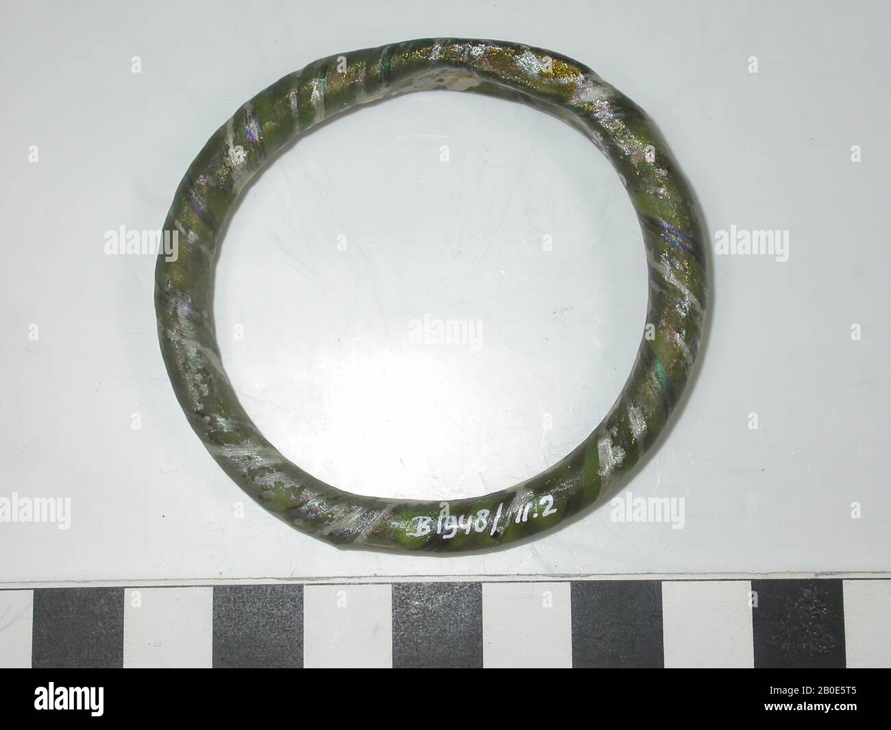 Bracciale in vetro verde oliva traslucido, leggermente appiattito nel punto in cui le due estremità sono fuse insieme. Avvolto con un filo fuso di vetro verde scuro. Bella iridescenza nei toni verde smeraldo., ornamento, vetro, D 6 cm, Siria Foto Stock