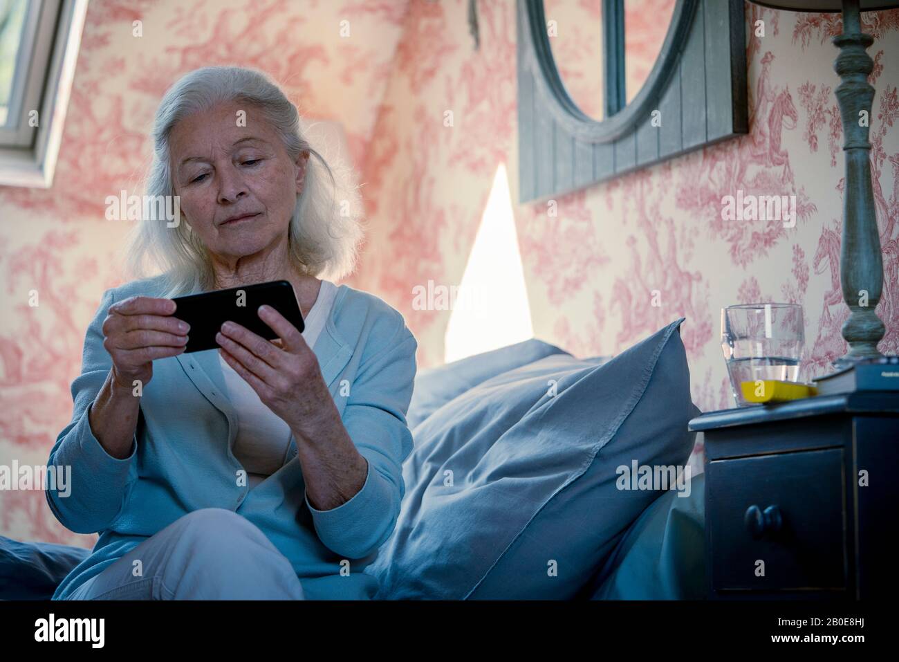Donna anziana che guarda i video sullo smartphone Foto Stock