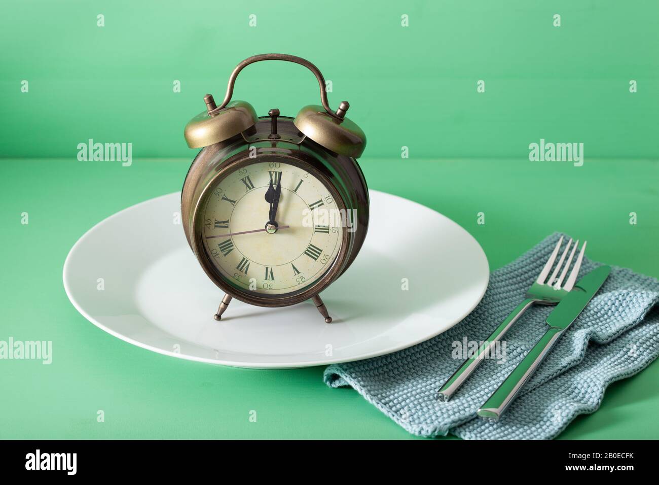 concetto di digiuno intermittente, dieta chetogenica, perdita di peso. forchetta e coltello su una piastra e alarmclock Foto Stock concetto di digiuno intermittente, dieta chetogenica, perdita di peso. forchetta e coltello su una piastra e alarmclock Foto Stock